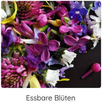 Bunte essbare Blüten auf einer schwarzen Platte